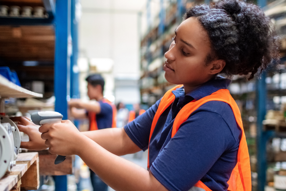 Vrouw die een product met een barcodescanner in een warehouse scant